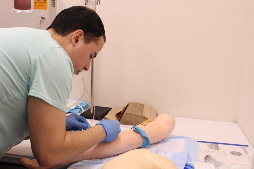 BCOM Student Hugo Gonzalez practices a blood draw procedure.