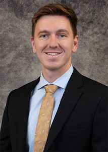 Portrait of Tyler Wilson in black suit with gray background
