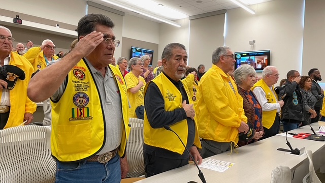 members salute at the Military members walking out the flags at Honor Flight Reunion attendees at Burrell College in New Mexico